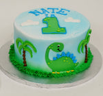 MaArthur's Bakery Custom Cake With Number 1 on Top and Green Dinasour and Palm Trees on Sides